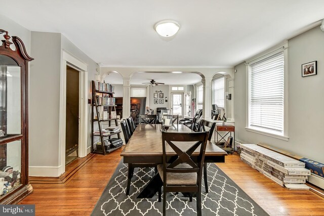 dining space with light hardwood / wood-style floors, decorative columns, and ceiling fan