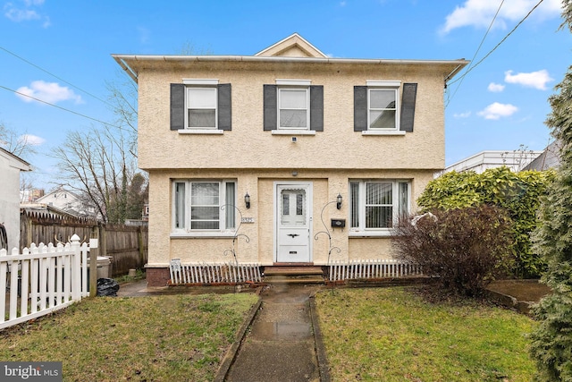 view of front of property with fence, a front lawn, and stucco siding