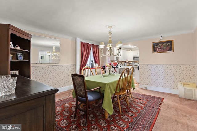 carpeted dining room featuring ornamental molding and an inviting chandelier