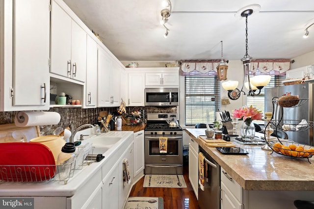 kitchen with dark hardwood / wood-style flooring, stainless steel appliances, decorative backsplash, white cabinetry, and track lighting