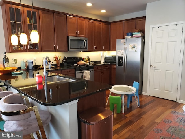 kitchen with stainless steel appliances, a kitchen breakfast bar, dark hardwood / wood-style flooring, kitchen peninsula, and sink