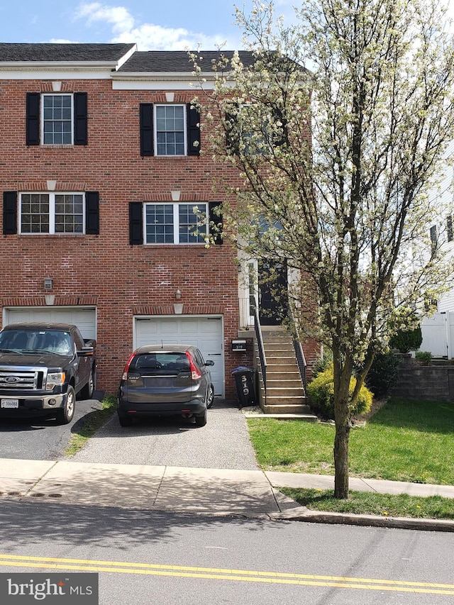 view of property featuring a garage and a front lawn