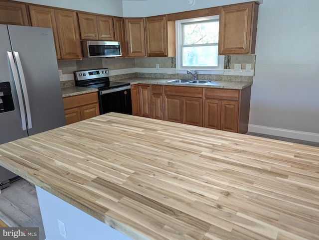 kitchen featuring light hardwood / wood-style flooring, backsplash, stainless steel appliances, and sink