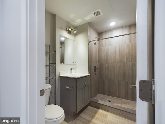 bathroom with a tile shower, vanity, and toilet