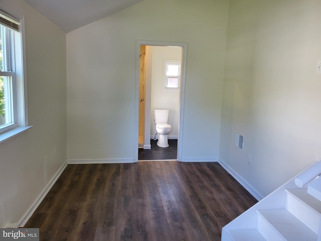 unfurnished bedroom featuring vaulted ceiling, ensuite bathroom, and dark hardwood / wood-style flooring