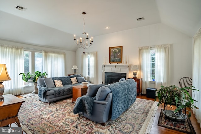 living area featuring lofted ceiling, visible vents, and a glass covered fireplace