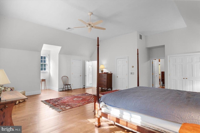 bedroom with lofted ceiling, wood finished floors, visible vents, and baseboards