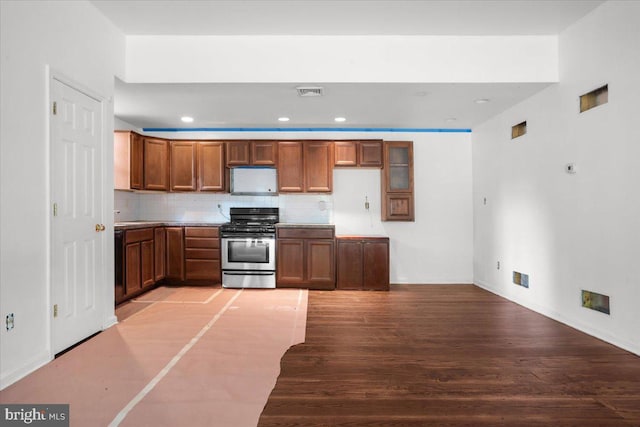 kitchen with stainless steel range with gas cooktop, visible vents, light wood-style flooring, decorative backsplash, and brown cabinetry