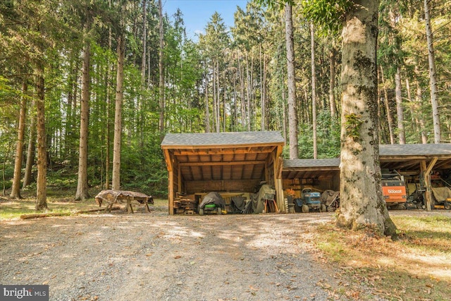 exterior space with an outbuilding, a pole building, a carport, and a view of trees