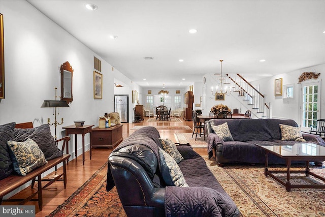 living area featuring a chandelier, recessed lighting, wood finished floors, visible vents, and stairway