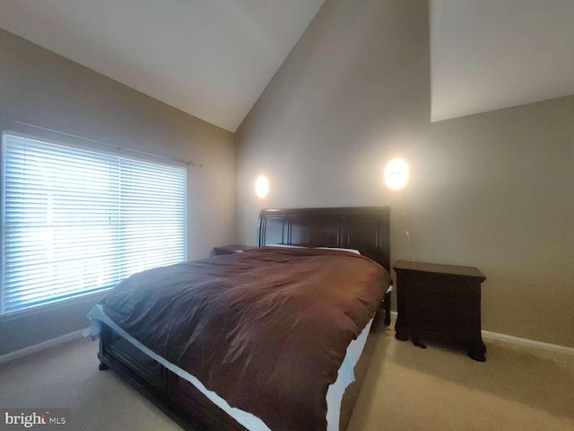 bedroom with light colored carpet and high vaulted ceiling