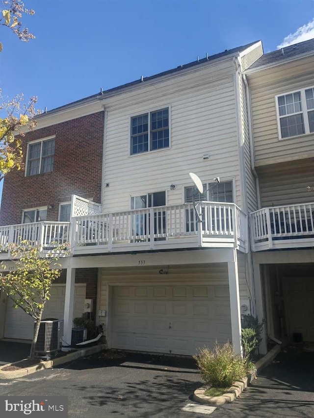 back of property featuring a garage and central AC unit