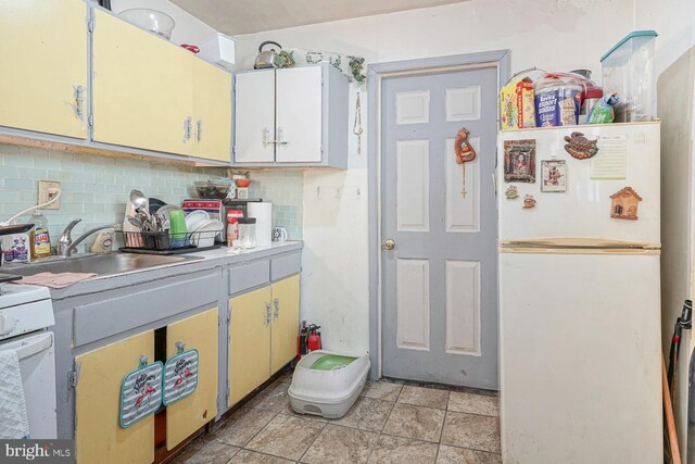 kitchen with decorative backsplash, white appliances, light tile patterned flooring, and sink