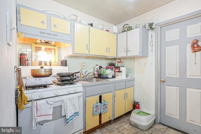 kitchen featuring backsplash, white gas stove, and sink