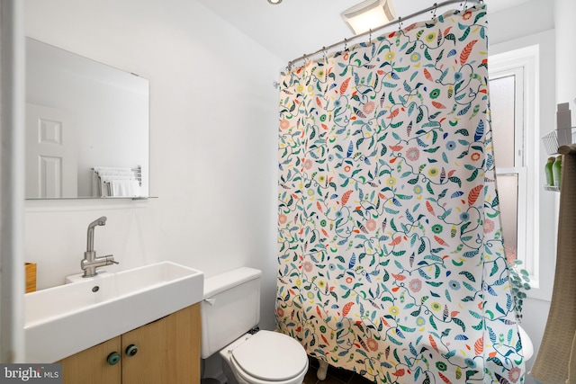 bathroom featuring walk in shower, vanity, and toilet