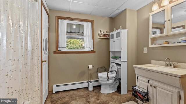 bathroom with vanity, baseboard heating, toilet, and a drop ceiling