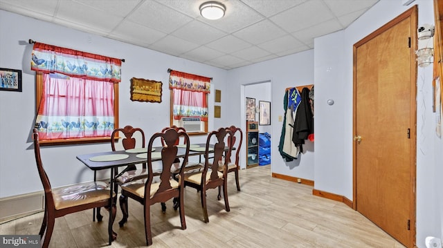 dining room featuring cooling unit, a drop ceiling, and light hardwood / wood-style flooring