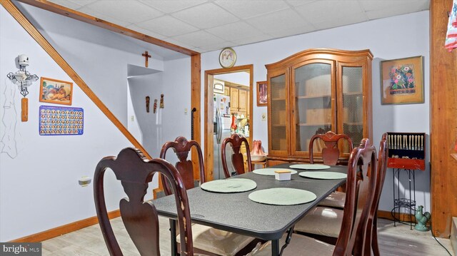 dining area featuring light wood-type flooring and a drop ceiling