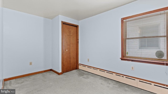 carpeted empty room featuring a baseboard radiator