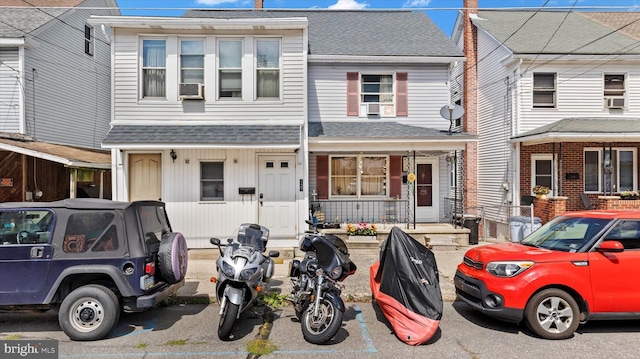 multi unit property with cooling unit, covered porch, and roof with shingles