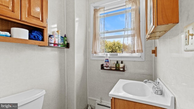 bathroom with a baseboard heating unit, vanity, toilet, and tile walls