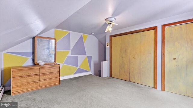 unfurnished bedroom featuring light carpet, lofted ceiling, two closets, and ceiling fan