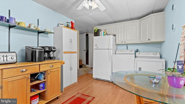 kitchen with independent washer and dryer, light hardwood / wood-style floors, ceiling fan, white refrigerator, and white cabinets