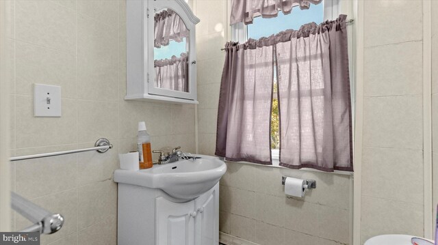 bathroom featuring vanity, toilet, a healthy amount of sunlight, and tile walls