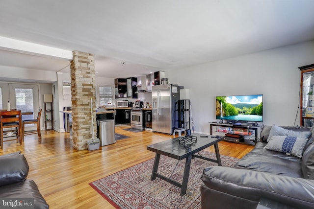 living room with light wood-type flooring, french doors, and ornate columns