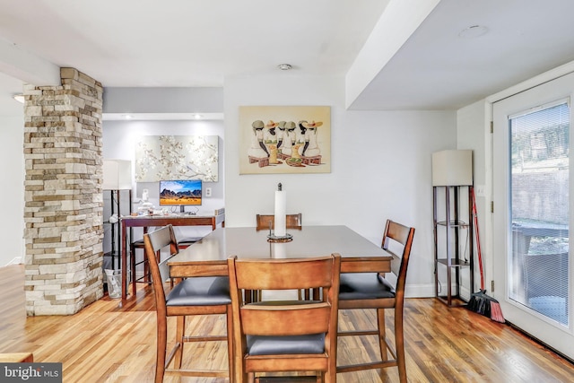 dining area with light hardwood / wood-style flooring and ornate columns