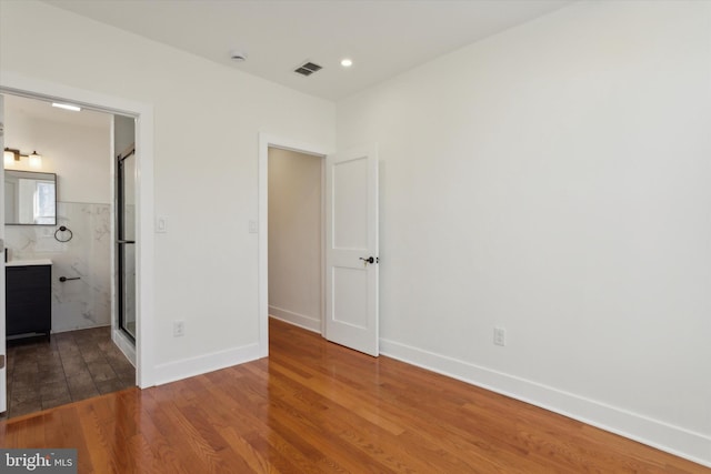 unfurnished bedroom featuring hardwood / wood-style floors and ensuite bathroom