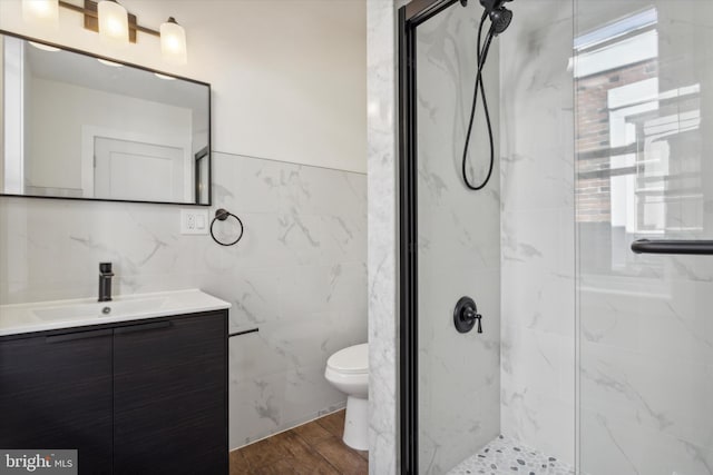 bathroom with hardwood / wood-style flooring, tile walls, toilet, vanity, and an enclosed shower