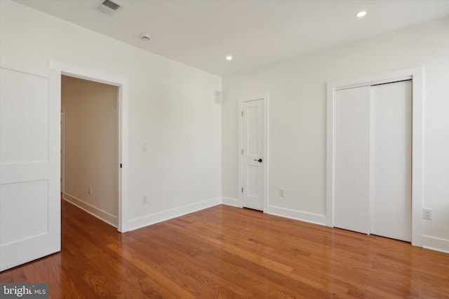 unfurnished bedroom featuring recessed lighting, wood finished floors, visible vents, and baseboards