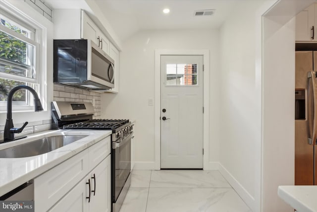 kitchen featuring visible vents, marble finish floor, a sink, stainless steel appliances, and decorative backsplash