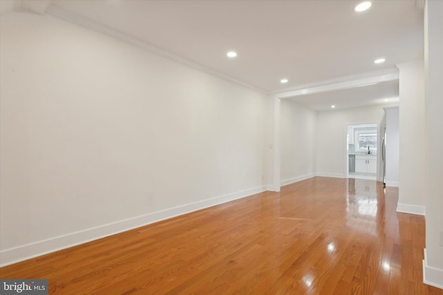 spare room featuring crown molding, recessed lighting, baseboards, and light wood-type flooring