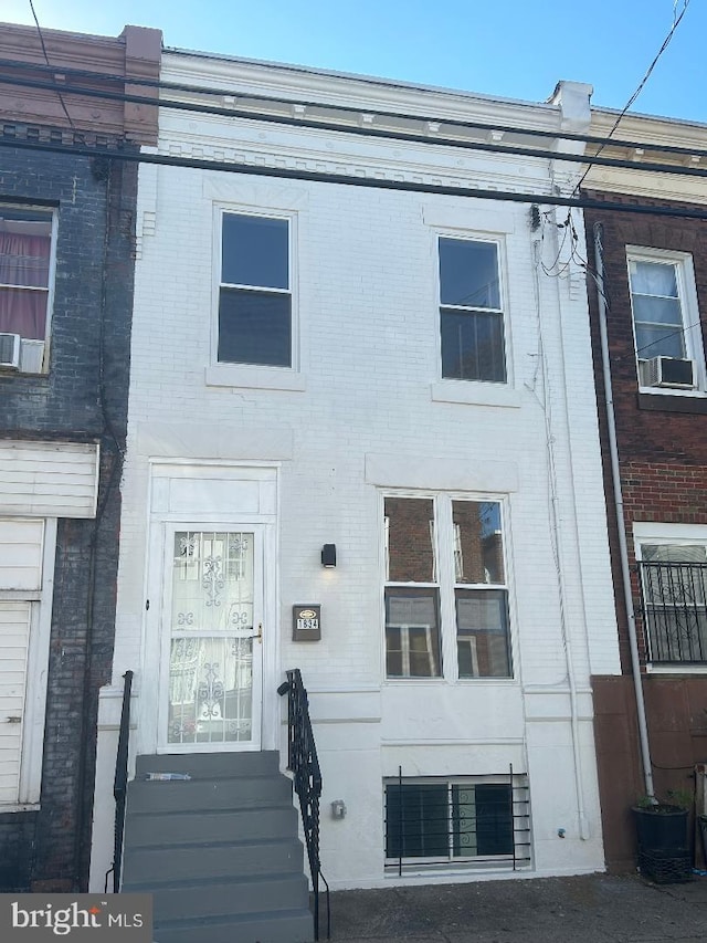 view of front facade with cooling unit and brick siding