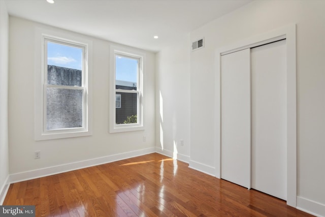 unfurnished bedroom with visible vents, baseboards, recessed lighting, wood finished floors, and a closet