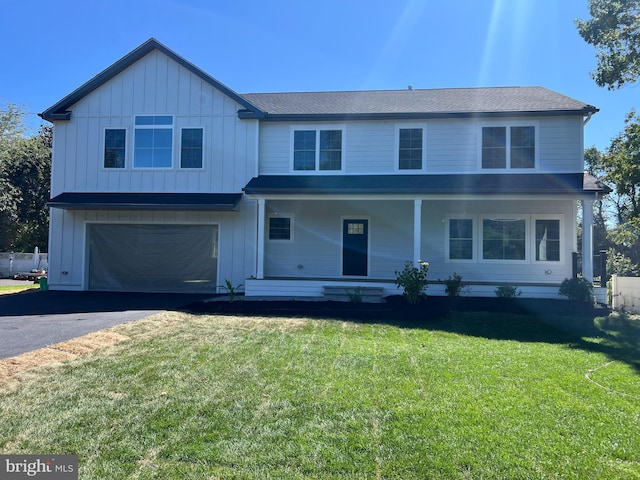 view of front of house with covered porch, a front yard, and a garage