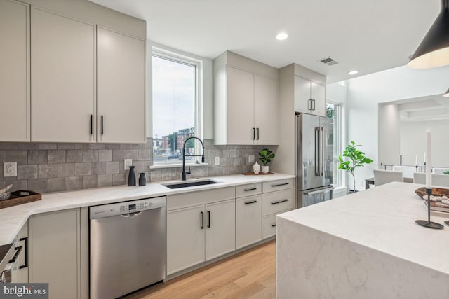 kitchen featuring tasteful backsplash, sink, stainless steel appliances, and light hardwood / wood-style flooring