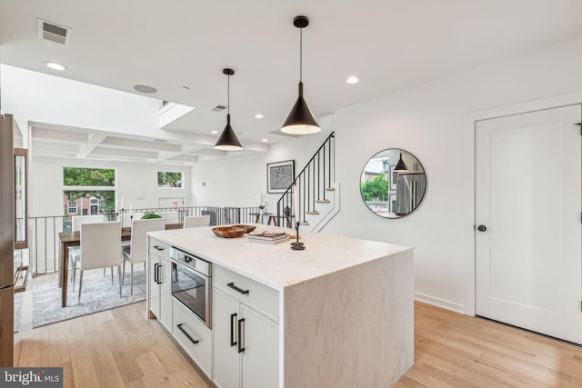 kitchen with pendant lighting, light hardwood / wood-style floors, white cabinets, and a center island