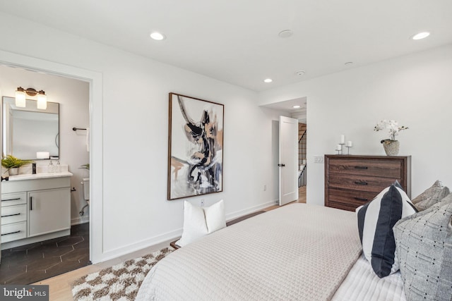 bedroom with dark hardwood / wood-style floors, sink, and ensuite bath