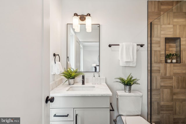 bathroom with a tile shower, vanity, and toilet