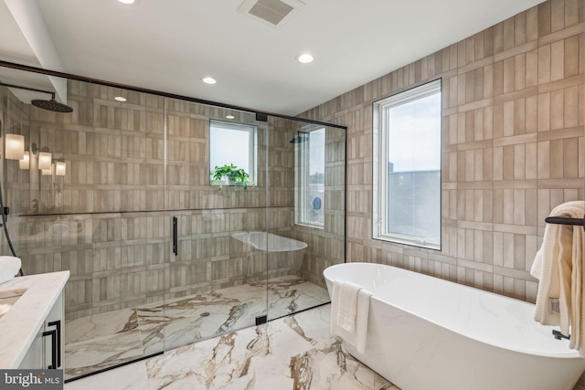 bathroom featuring tile walls, vanity, and plus walk in shower