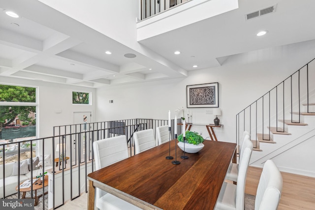 dining area with light hardwood / wood-style floors, beamed ceiling, and coffered ceiling