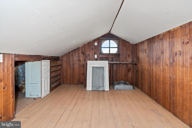 bonus room featuring wooden walls, vaulted ceiling, and light wood-type flooring