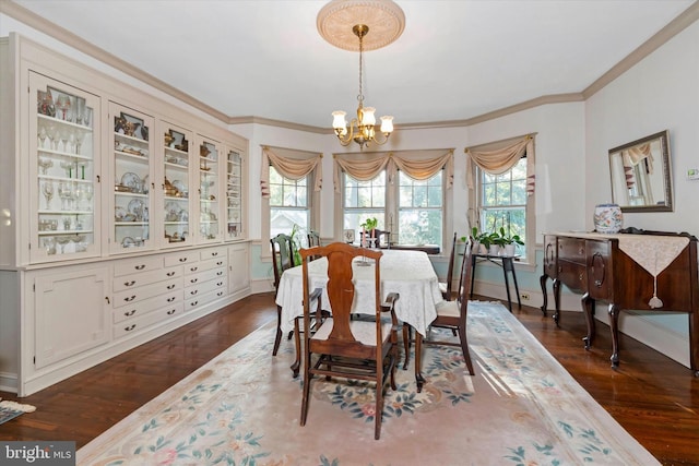 dining room featuring dark wood-type flooring, a notable chandelier, and ornamental molding