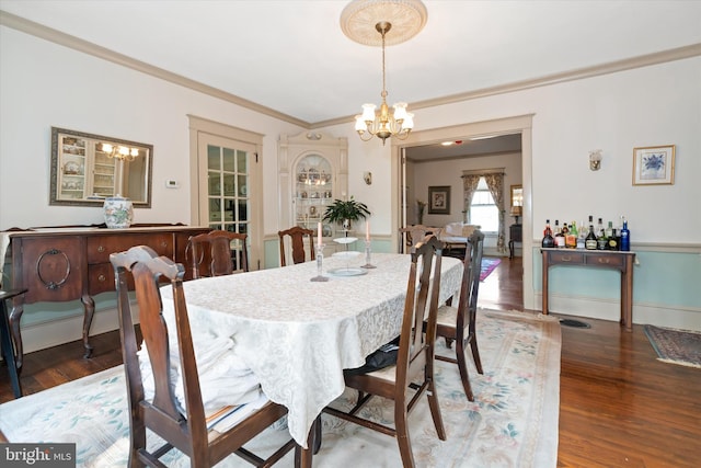 dining room featuring a chandelier, crown molding, and dark wood-type flooring