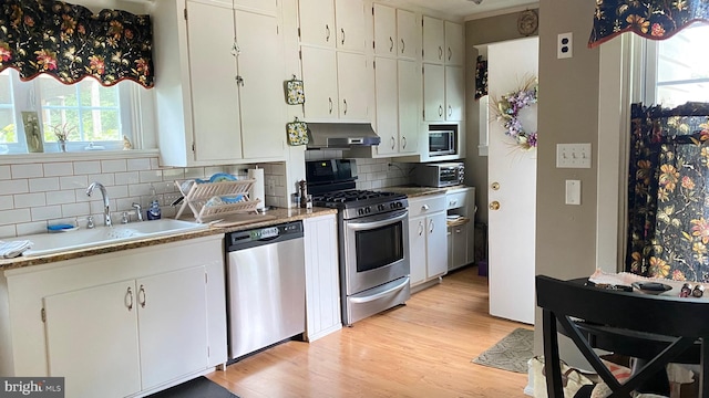 kitchen with sink, white cabinetry, exhaust hood, and appliances with stainless steel finishes