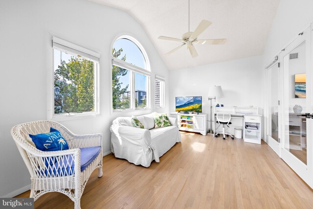 living room with ceiling fan, lofted ceiling, and light wood-type flooring