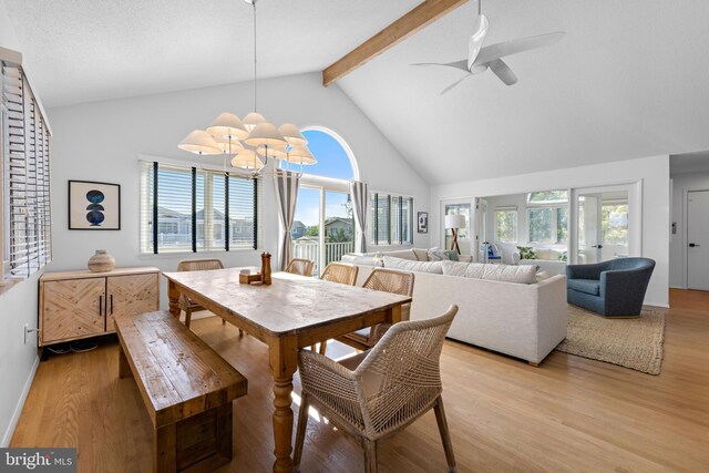 dining area featuring light wood-type flooring, ceiling fan with notable chandelier, beam ceiling, and a wealth of natural light